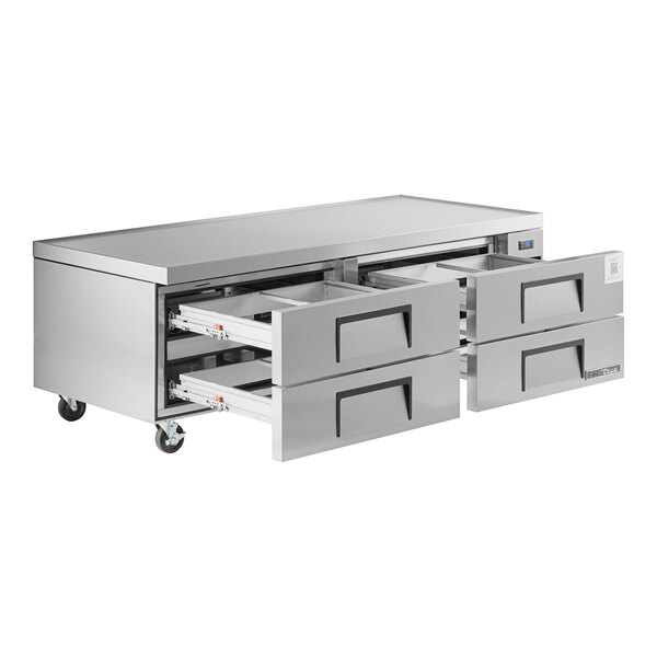 A stainless steel refrigerated chef base with four pull-out drawers and caster wheels.