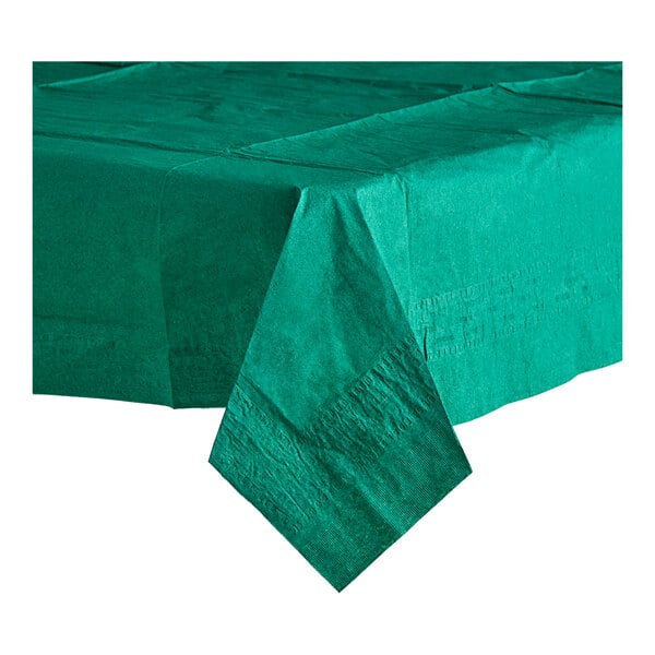 A folded green Table Mate tissue/poly table cover with a green napkin on a table.