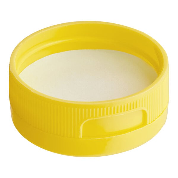 A close up of a yellow plastic cap with a white circle inside.