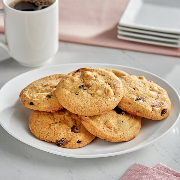 A plate of Otis Spunkmeyer red, white, and blue cookies with a mug of coffee on a white table.