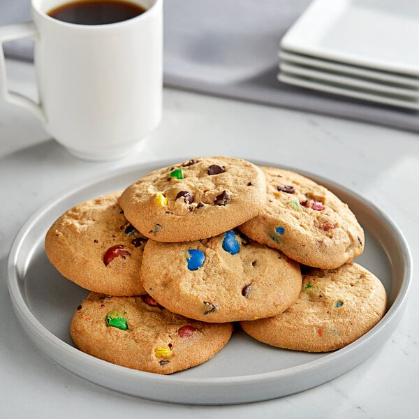 A plate of Otis Spunkmeyer chocolate chip cookies on a table with a cup of coffee.