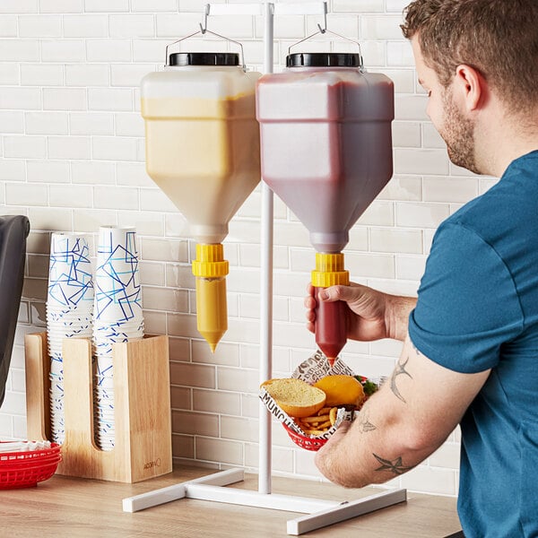 A man using an Asept condiment pump to put ketchup on a burger.