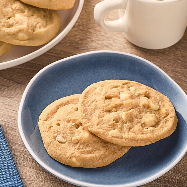 A plate of Otis Spunkmeyer white chocolate macadamia nut cookies on a table.