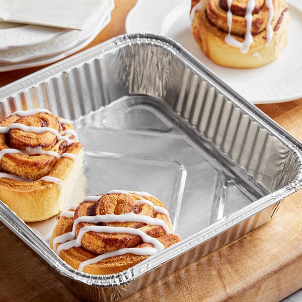 A Baker's Lane foil cake pan with cinnamon rolls on a table.