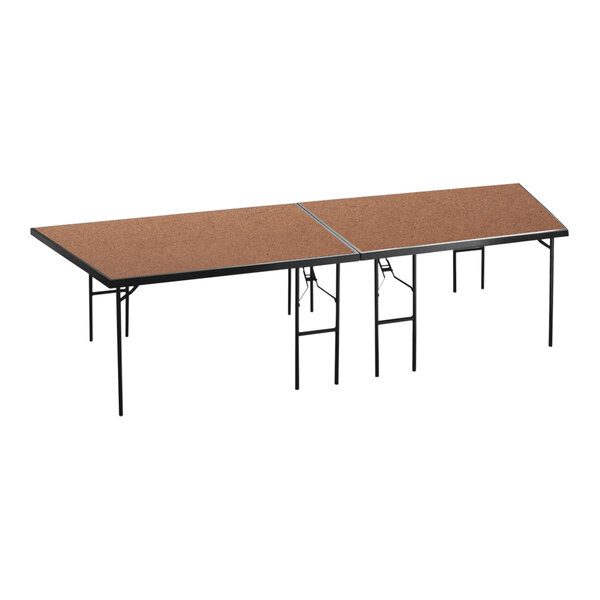 A National Public Seating rectangular stage pie on a table with brown hardboard surfaces.