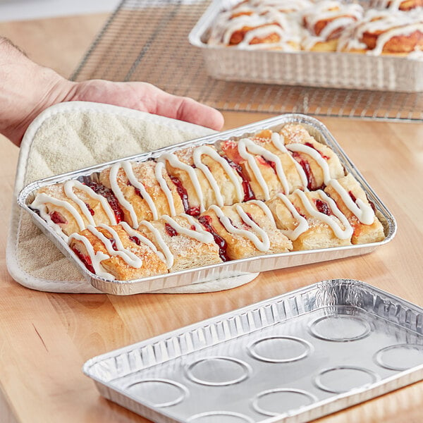 A hand holding a Baker's Lane aluminum foil tray with pastries inside.