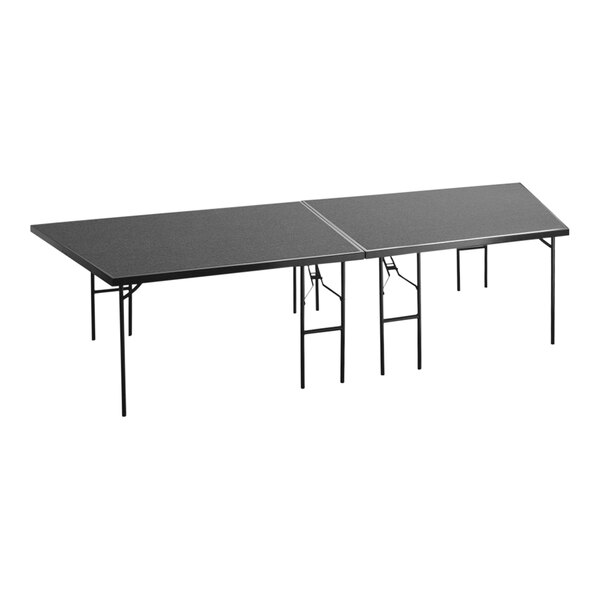 A National Public Seating rectangular black carpet stage pie table with folding legs.