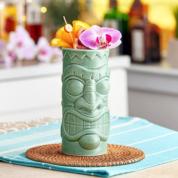 A green Acopa ceramic tiki mug with a flower in it.