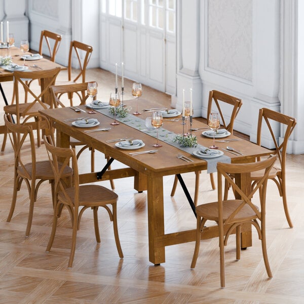 A Lancaster Table & Seating Vineyard Series barrel brown table set with 6 cross back chairs set up for a dinner party.