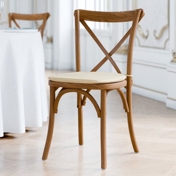 A Lancaster Table & Seating outdoor cross back chair with a Chardonnay tan cushion.