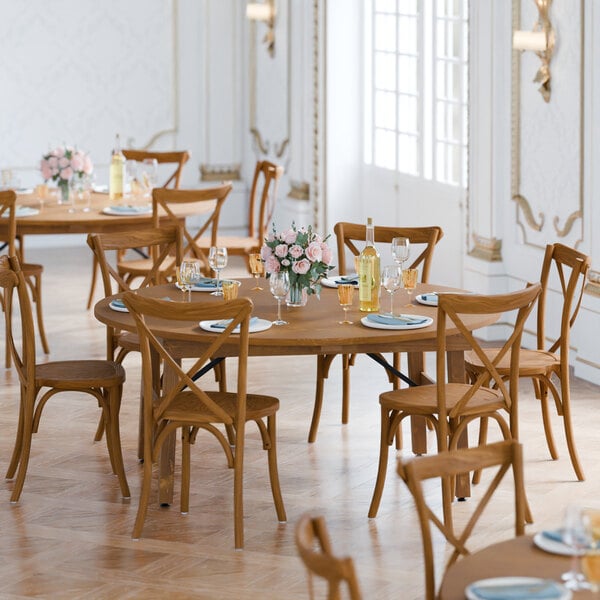 A Lancaster Table & Seating Vineyard Series round wooden table and chairs set up for a dinner party.