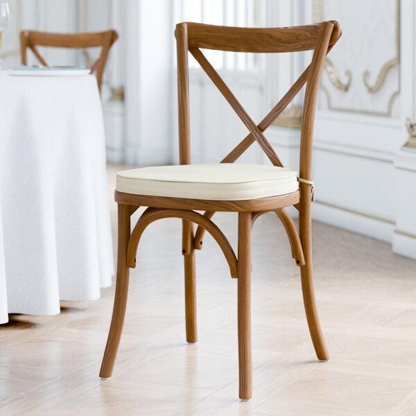 A brown outdoor cross back chair with a white cushion.