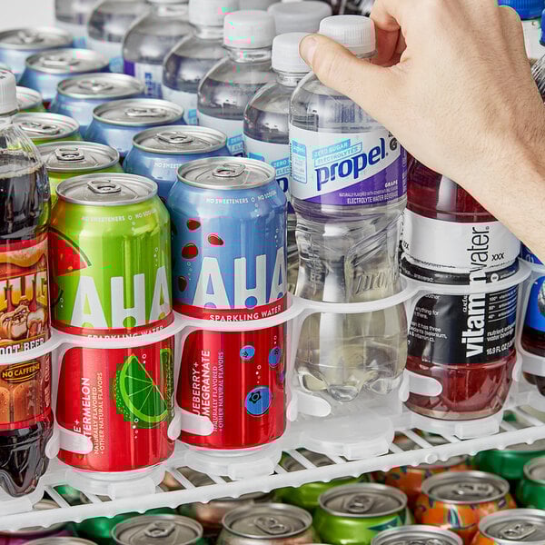 A person organizing clear soda bottles in a 10 lane universal gravity feed bottle organizer.