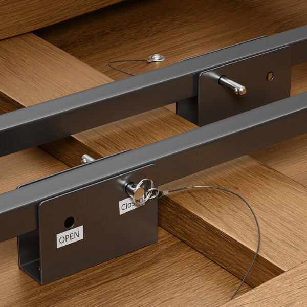 A brown wooden round table with two metal bars attached to it and eight wooden chairs with metal bars attached to them.