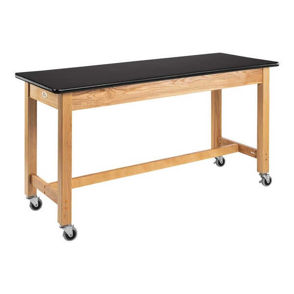 A wooden National Public Seating science lab table with a black top and casters.