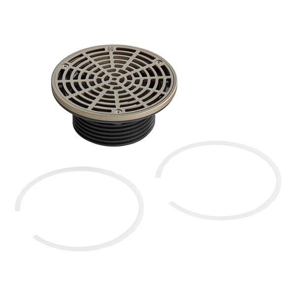 A circular metal Sioux Chief floor drain cover with black and silver rings.