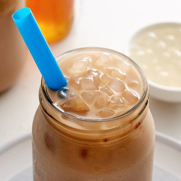 A glass jar with a straw filled with brown Bossen Original Crystal Boba and ice.