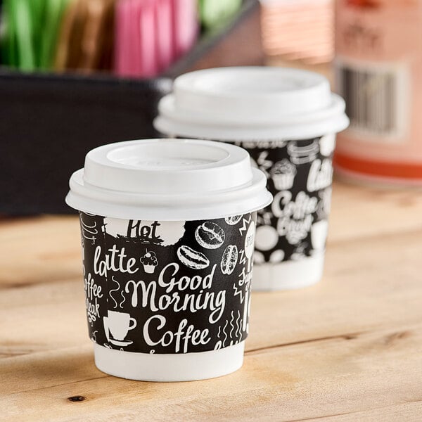 Two Choice double wall paper coffee cups with a Coffee Break print and lids on a table.