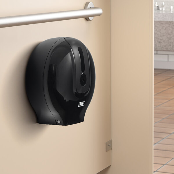 A black Lavex single roll toilet paper dispenser with a round hole on a wall.