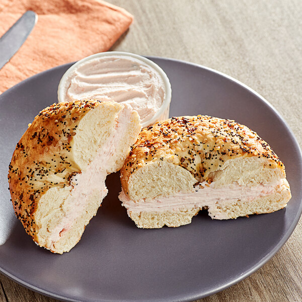 A bagel sandwich with cream cheese and a knife on a plate.