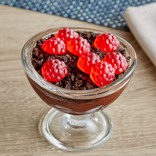 A glass bowl of Albanese Berry Red Gummi Raspberries on a table.