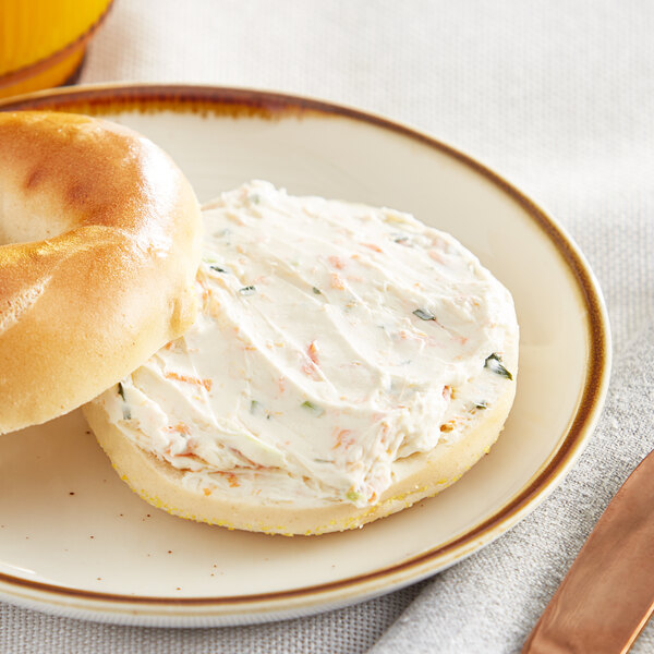 A bagel with Melanie's Medleys vegetable cream cheese on a plate.