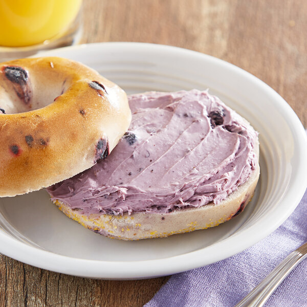 A bagel with Melanie's Medleys blueberry spread on it on a plate.