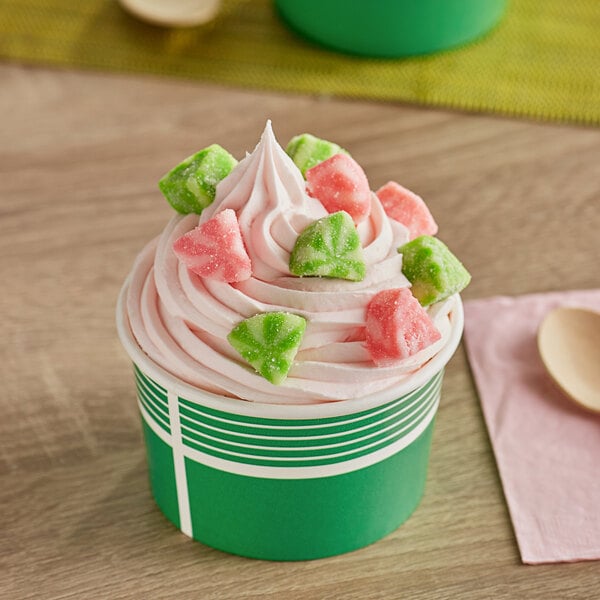 A close up of pink and white Albanese Watermelon Gummi Slices on a green and white surface.