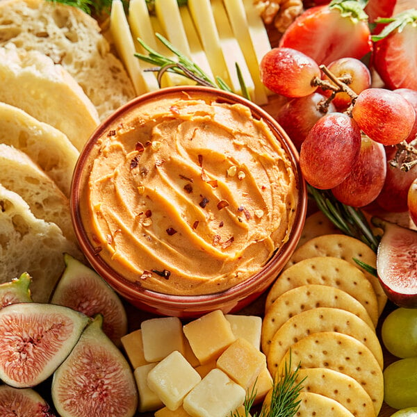 A bowl of Don's Salads Chipotle Cheddar Cheese Spread with crackers, cheese, and fruit.