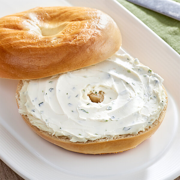 A bagel with Don's Salads chives cream cheese on a white plate.