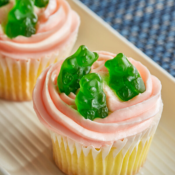 A cupcake with green frosting and Albanese Green Apple Gummi Bears on top.