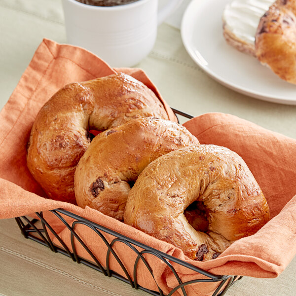 Just Bagels chocolate chip bagels in a basket on a table.