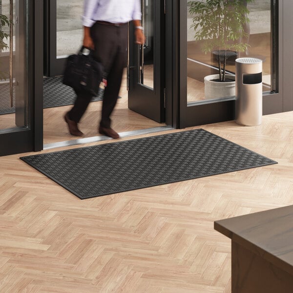 A man walking on a black Lavex Parquet entrance mat.
