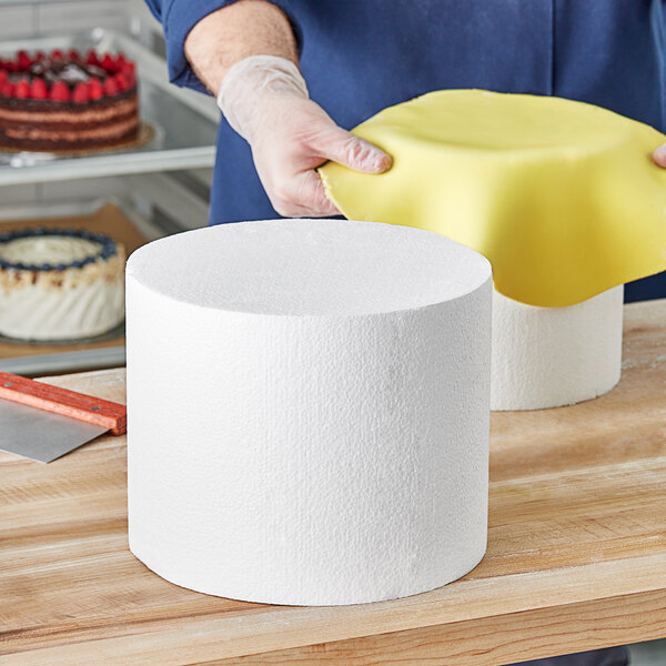 A man holding a Baker's Lane foam round cake dummy.
