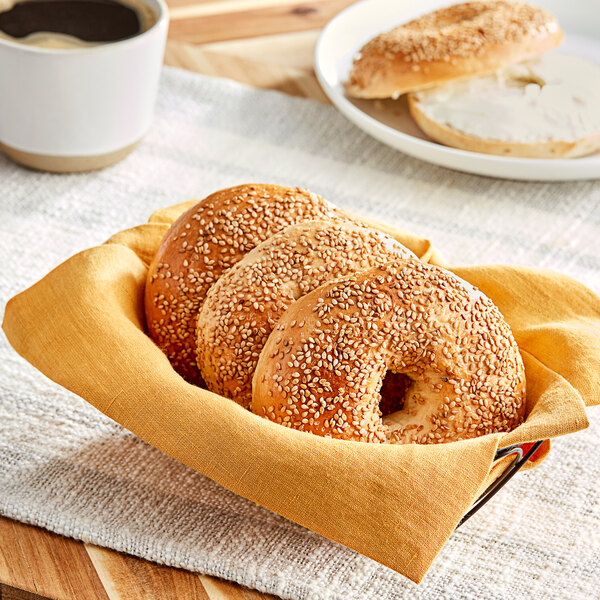 A basket filled with sesame bagels on a table in a breakfast diner.