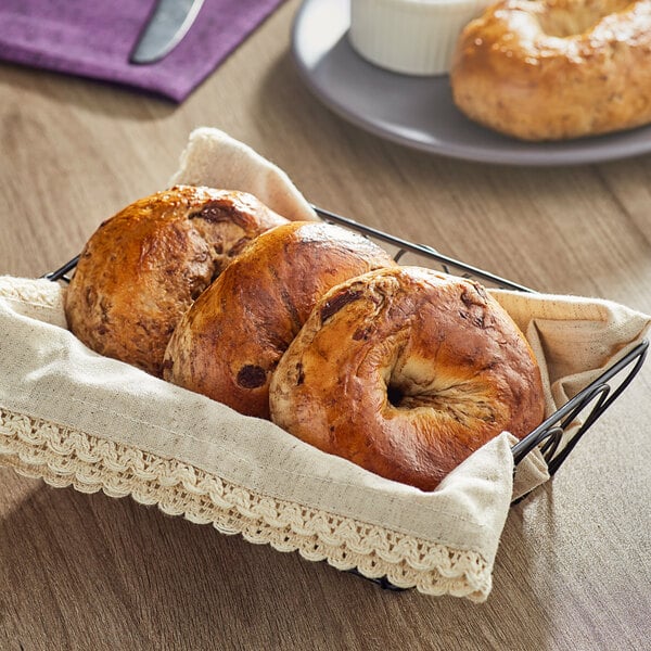 Just Bagels Cinnamon Raisin Bagels in a basket on a table.