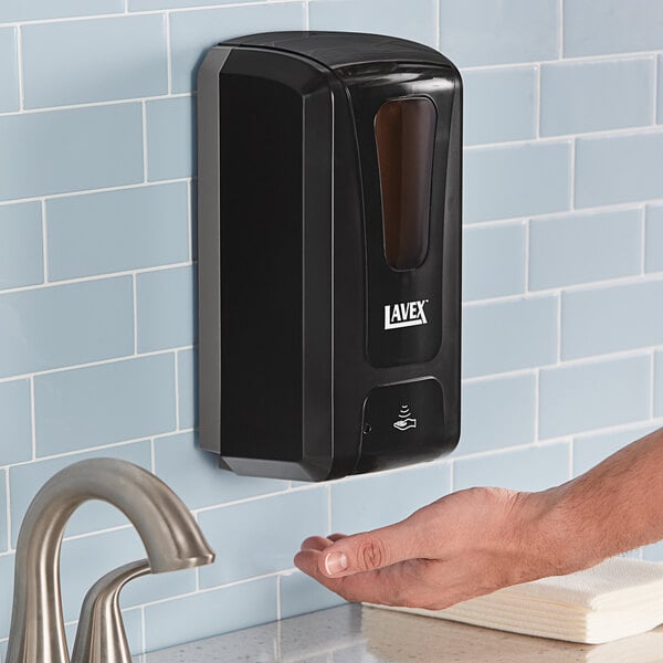 A person using a black Lavex automatic liquid soap dispenser.