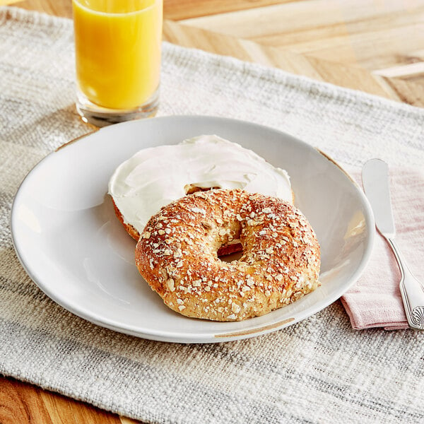 A multigrain bagel with cream cheese on a plate.