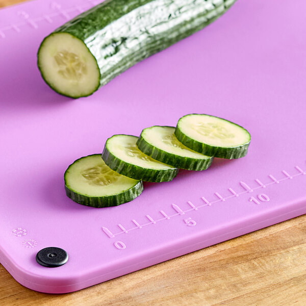 A cucumber slice on a purple Choice cutting board.