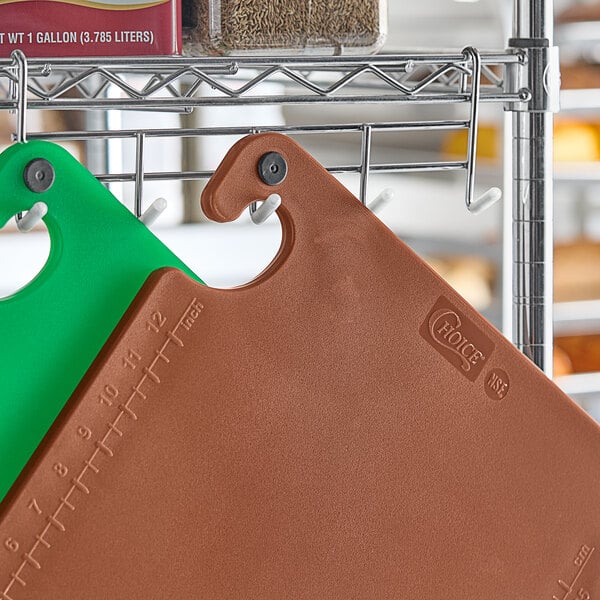 A brown Choice cutting board with green grips.