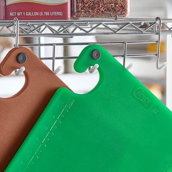 A green Choice cutting board with grips and rulers on a metal rack.