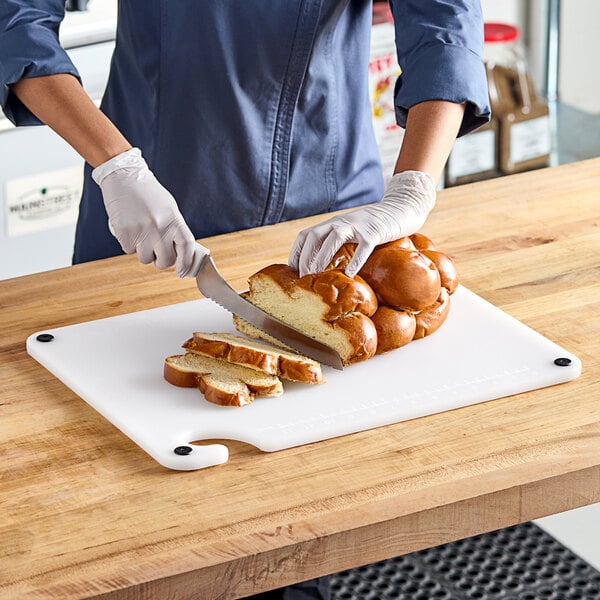 A person cutting a loaf of brown bread on a Choice white cutting board.