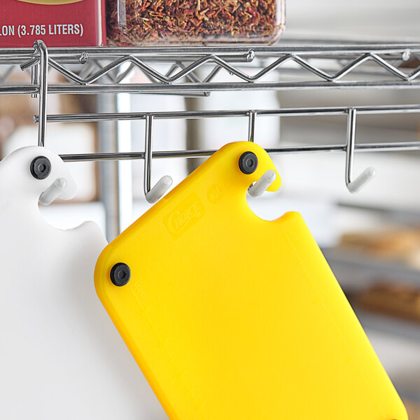 A yellow Choice cutting board on a metal rack with a hook.