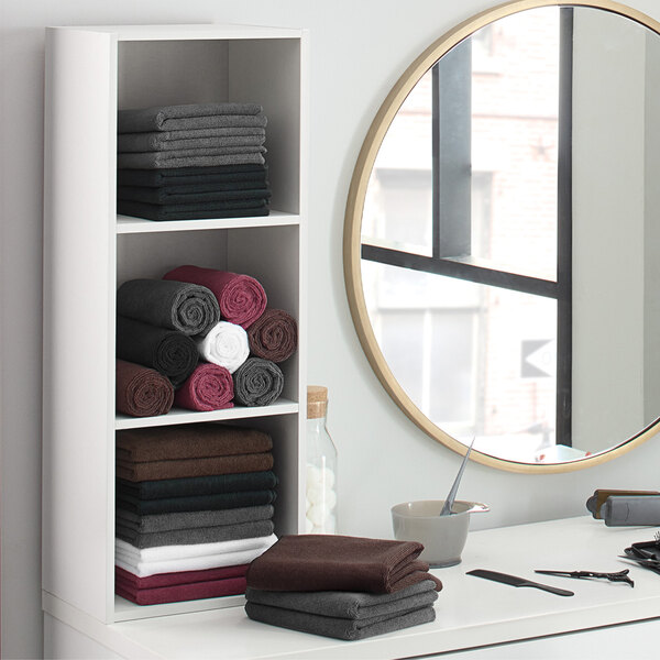 A shelf with Monarch Brands gray microfiber hand towels over a white bowl on a shelf above a mirror.