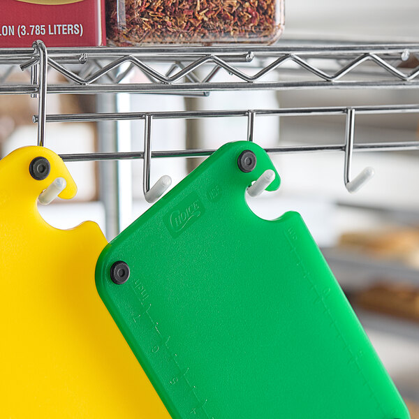 A green Choice cutting board with grips and rulers on a metal rack.