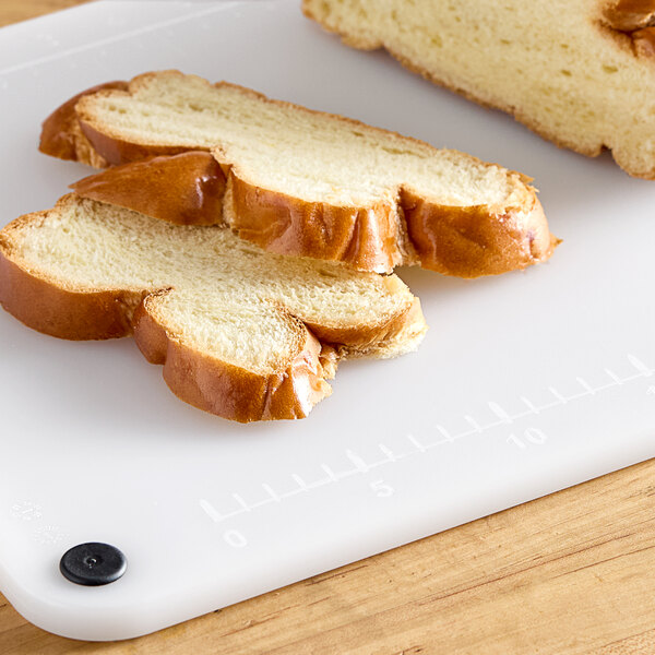 A sliced loaf of bread on a white Choice cutting board.
