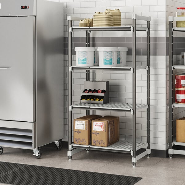 A Cambro Elements XTRA Camshelving unit in a school kitchen with white containers and boxes on it.
