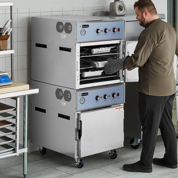 A man opening a Cooking Performance Group CHUC2B SlowPro Stacked Cook and Hold Oven.