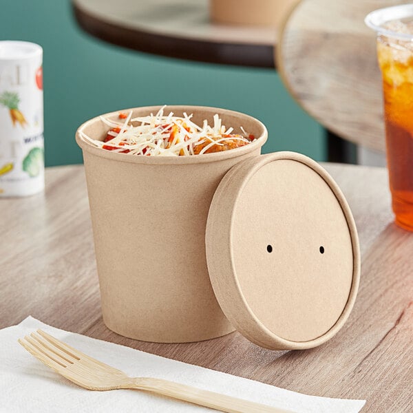 A Choice kraft paper food container with a vented lid on a table full of food.