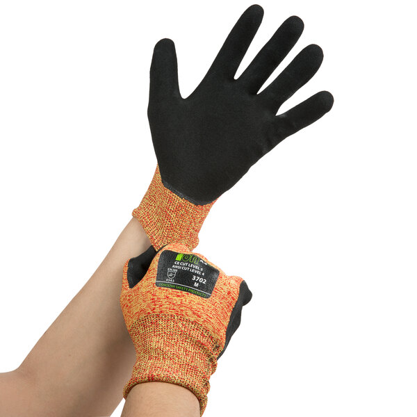 A pair of extra small Cordova orange and black cut-resistant gloves on a person's hands.